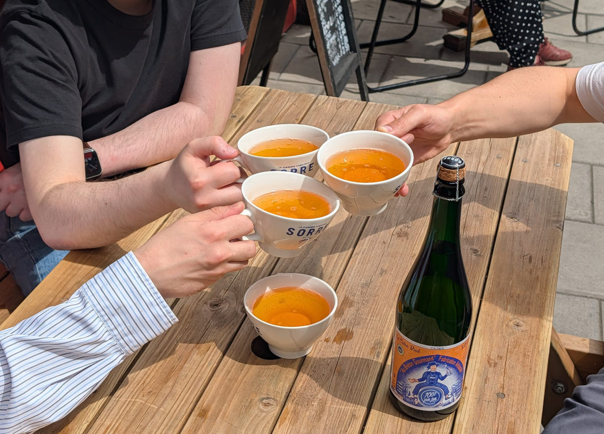 Friends toasting with bowls of Breton cider at Chez Marcel